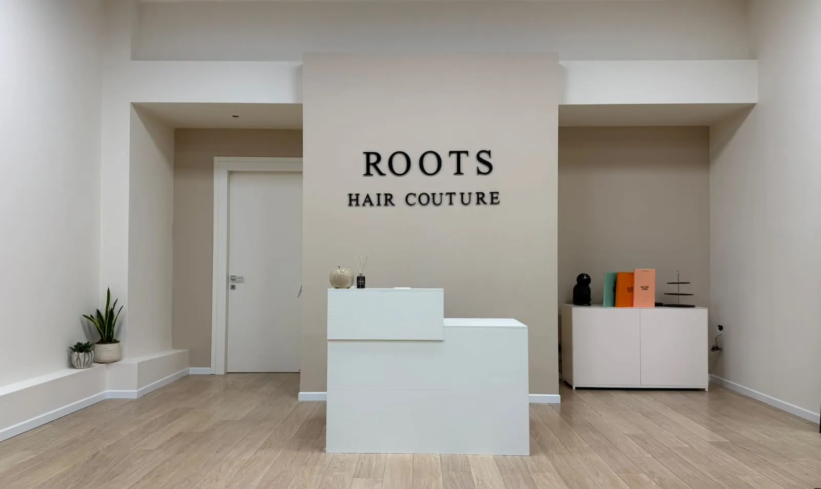 La reception del salone ROOTS Hair Couture con l'insegna a parete